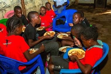 Children in red and black jerseys eating lunch together